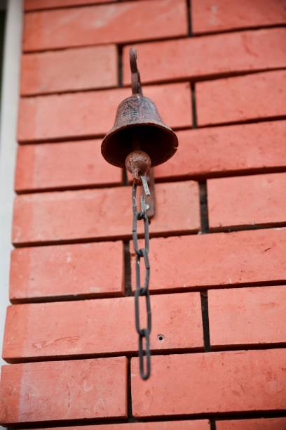 istock Vertical shot of an old rusty bell hanging on a brick wall 1447312771