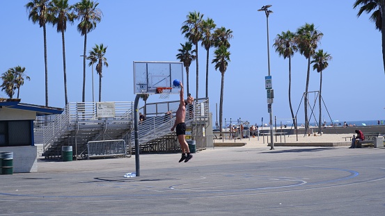 los angeles, United States – November 15, 2022: A young man throwing a ball into a basketball hoop on a sunny day