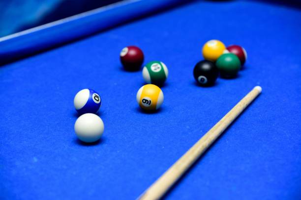 istock Closeup of a blue pool table with balls and a cue stick. 1447315529