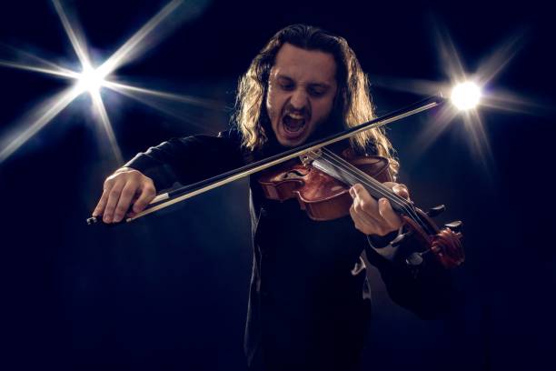 istock Man angrily playing the violin under spotlights 1447315757