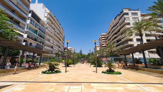 Costa del Sol, Spain – July 17, 2019: The Avenue de Mar on a warm lazy afternoon with tourists walking on he street
