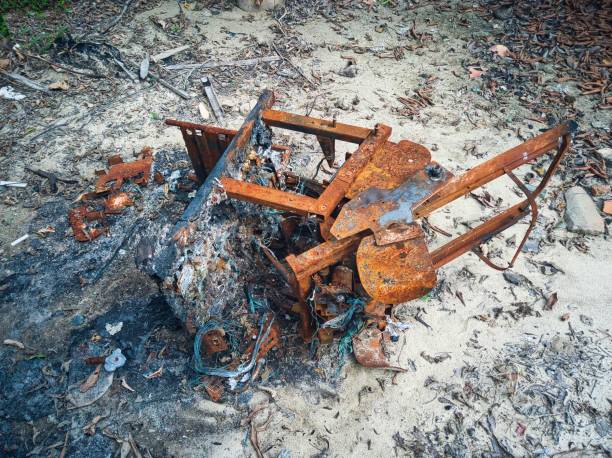 ripresa ad alta angolazione di una poltrona da massaggio bruciata e arrugginita su un mucchio di cenere - burnt furniture chair old foto e immagini stock