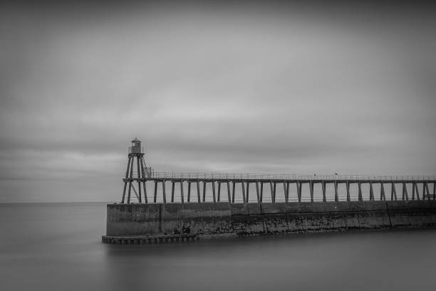 istock Pier at Whitby beach, UK in grayscale in cloudy weather 1447320302