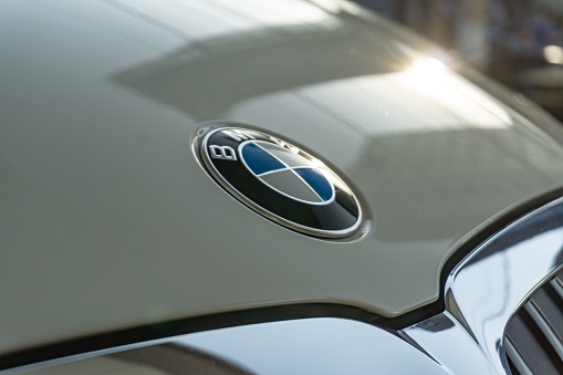 Belo Horizonte, Brazil – October 06, 2022: A closeup shot of the BMW logo on a hood badge with the sunlight reflection