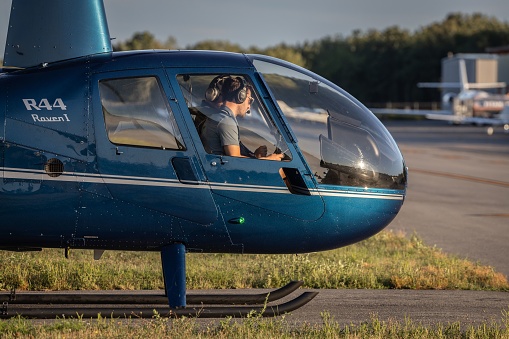 Norwood, United States – August 31, 2022: A selective shot of a flight instructor with a student learning to fly a Robinson R44 helicopter outside of Boston