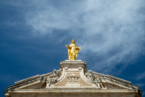 The golden statue on the roof of Basilica of Saint Mary of the Angels. Assisi, Italy.