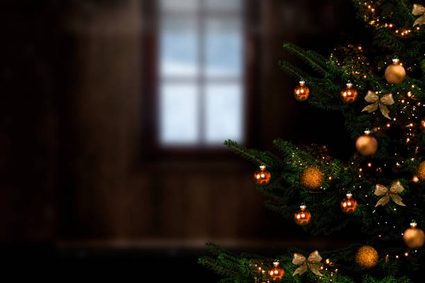 Christmas tree with golden balls against blurred background with window