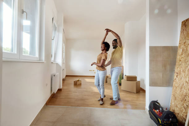 Happy black couple having fun while dancing in their new home.