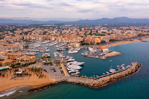 Aerial view of seaside area of French town of Frejus on Mediterranean coast overlooking residential houses and marina for pleasure yachts in summer