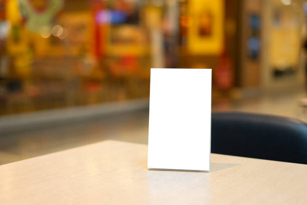 istock Mock up Label the blank menu frame in Bar restaurant ,Stand for booklets with white sheets paper acrylic tent card on wooden table cafeteria blurred background can inserting the text of the customer. 1447340744