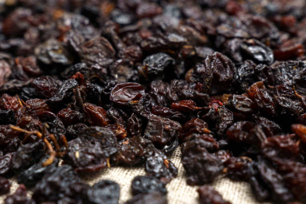 istock Dried black raisins in bowl with fresh organic grapes, background, selective focus 1447341768