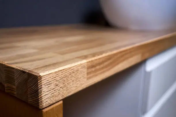 Solid ash glued timber corner table top closeup. Bathroom interior contemporary design countertop tabletop, with sink.