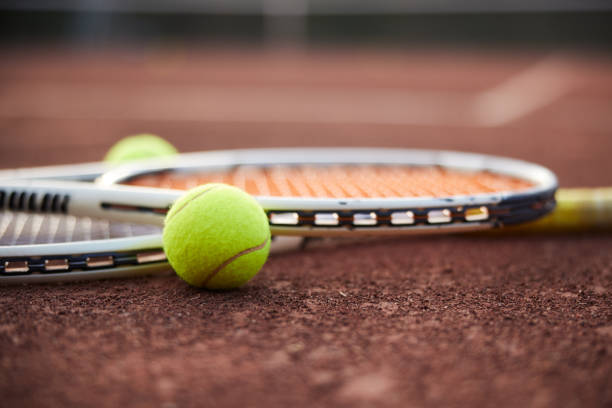 tennisschläger und bälle auf einem sandplatzbelag - tennis court tennis ball racket stock-fotos und bilder