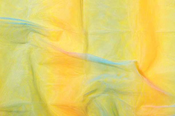 istock Silk fabric transparent. Yellow twisted twirl fabric multicolour texture 1447342980