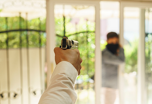 Male landlord holding gun against thief