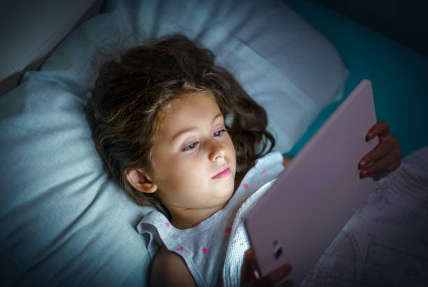 istock Little girl using digital tablet in her bed at night 1447343568