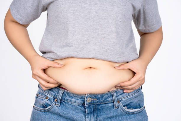 istock Woman's hand holding belly on white background with copy space. Obesity concept. 1447344468