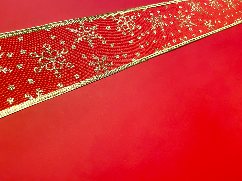 Gold and red colored ornate Christmas ribbon on the red background with copy space