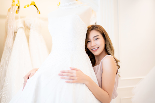 In the background of wedding dresses, an Asian woman designer manages a wedding business., Wedding designer and SME start up concept.