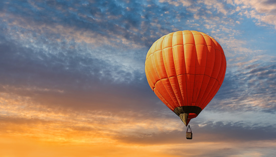 Orange hot air balloon against the backdrop of an expressive sunset sky