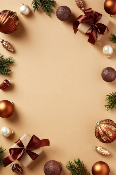 istock Christmas frame. Brown Xmas baubles decorations, ornaments, fir branches, gift boxes on beige background. Christmas vertical banner design, New Year holiday poster template. 1447352381