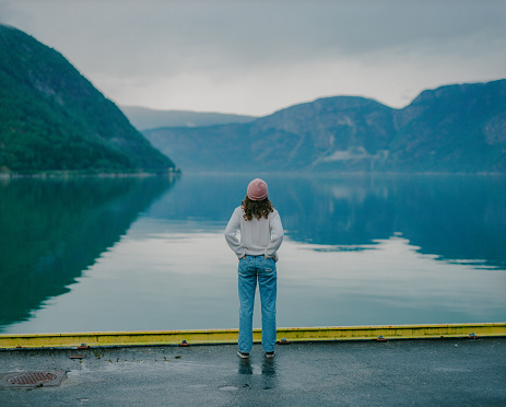 Young Caucasian woman standing on the background of the fjord