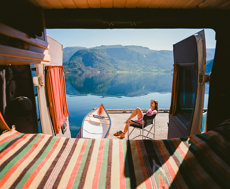 Young Caucasian woman resting near the camper van  near the lake in Norway