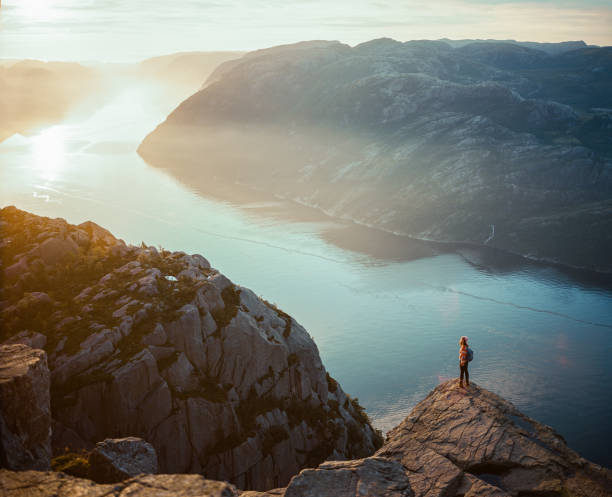 frau, die in den bergen vor dem hintergrund des lysefjords wandert - lysefjord stock-fotos und bilder