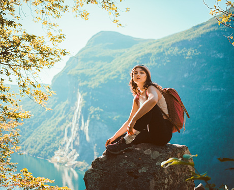 Young Caucasian woman sitting near Seven sisters  waterfall in mountains in Norway