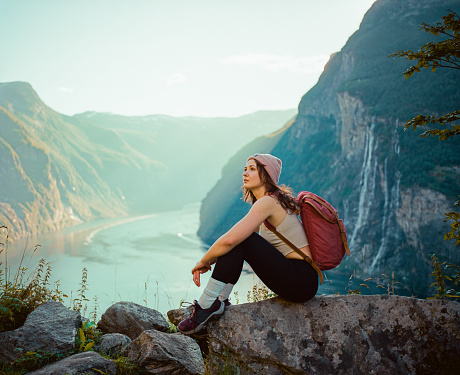 Young Caucasian woman sitting near Seven sisters  waterfall in mountains in Norway
