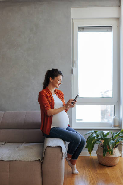 istock Pregnant woman texting at home. 1447357090