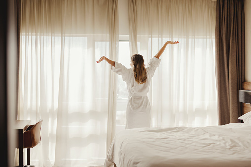 Easy lifestyle woman waking up in weekend morning taking some rest relaxing in comfort city hotel room enjoying world lazy day, having happy life quality balance concept