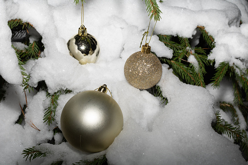 This is a photograph of blue and white and Silver Christmas ornaments shot in the snow on a white wooden background. There are no people in the photograph