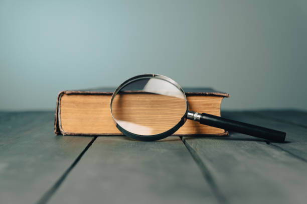 istock Book and magnifier on wooden table 1447360385