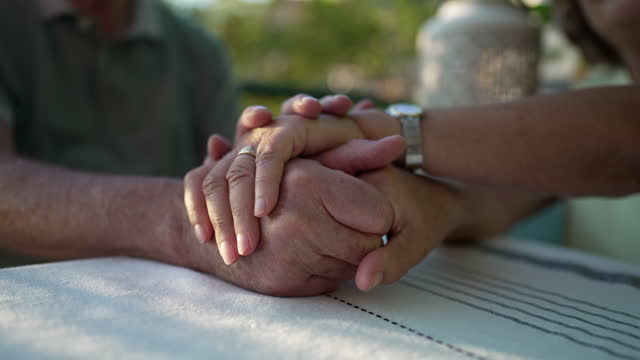 Mature couple holding hands together. Close up of senior man and woman in romantic caring moment. Love and resilience concept