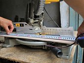 taking measurements on a wooden plank when working with a miter saw