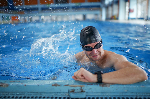 Young man checking his heart rate on a smartwatch before swimming in the swimming pool