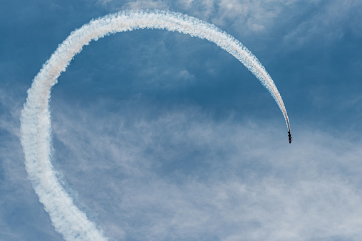 two airplanes fly in parallel describing a white parabolic trajectory over the blue sky. condensation trails. concept synchronization and tuning