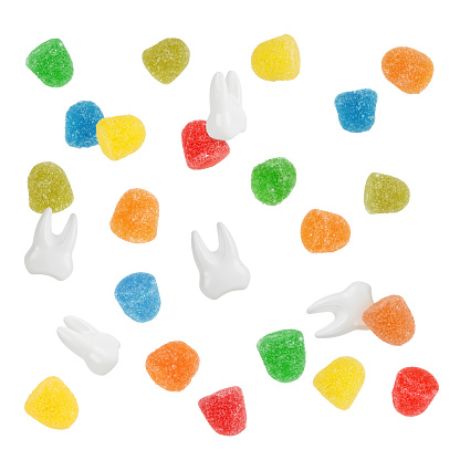Colorful candies gumdrops and white teeth are falling together symbol of teeth caries.