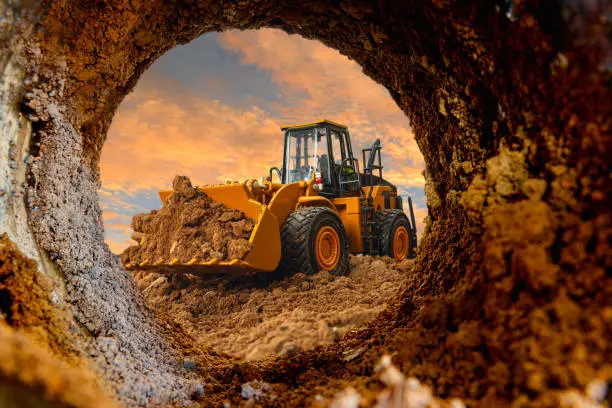 Wheel loader are digging the soil in the tunnel construction site on the sky background