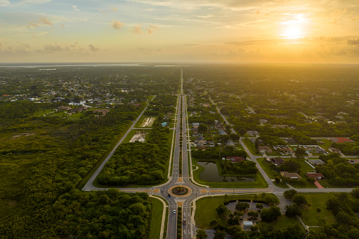 Aerial view of american suburban area with rural road roundabout intersection with moving cars traffic. Circular transportation crossroads in Florida.