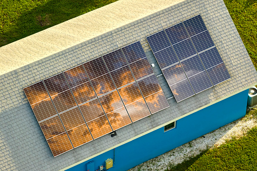 Aerial view of typical american building roof with rows of blue solar photovoltaic panels for producing clean ecological electric energy. Renewable electricity with zero emission concept.