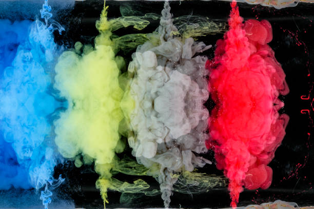 A needles from which the red, yellow, blue and gray paint flows into bowl of water on a black background