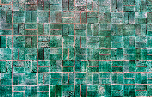 An exterior wall of plain green tiles.