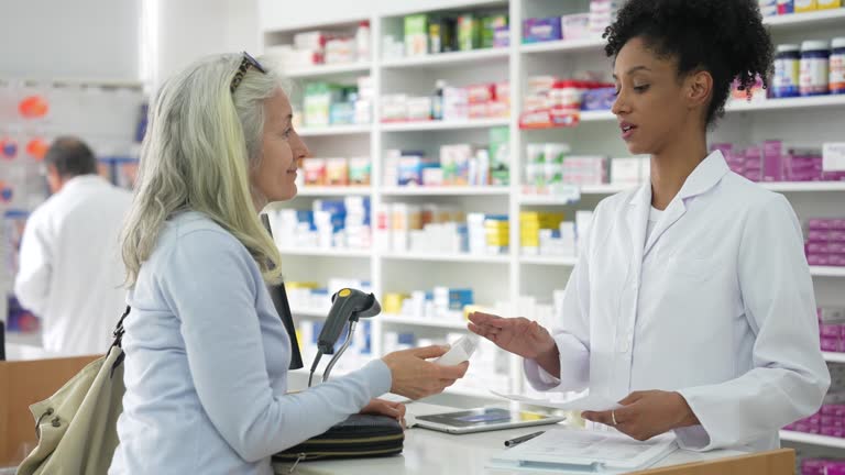 Adult woman recieving medicine from African American pharmacist while standing at counter