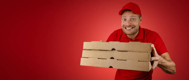 istock funny delivery man with pizza boxes on red background. banner with copy space 1447391036
