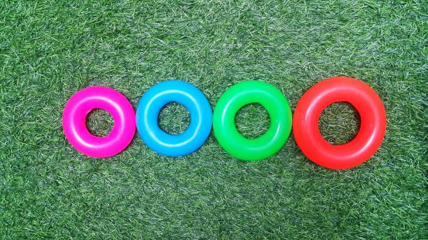 disposition des anneaux de jouets en plastique sur du gazon vert artificiel - plastic hoop plastic bracelet fashion photos et images de collection