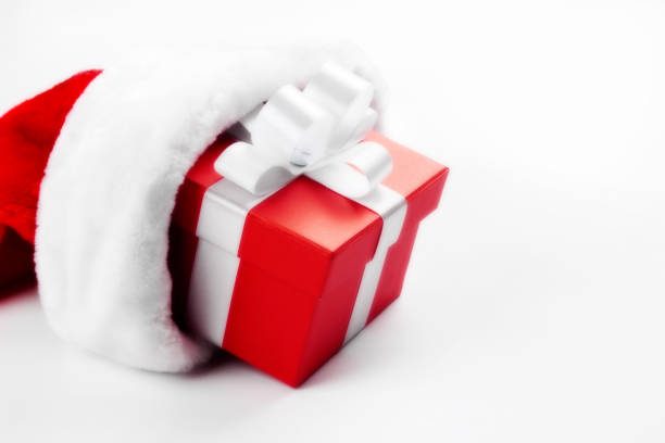 Red gift box in red Santa hat. Copy space. White background. No people. Horizontal orientation.