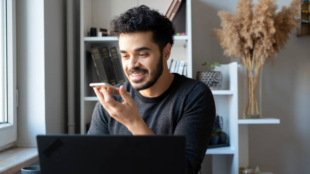 istock Young man working with laptop and recording voicemail 1447398469