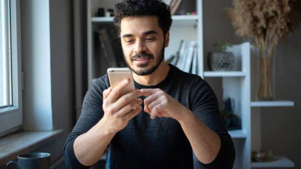 istock Young man surfing internet with phone at his desk 1447398612